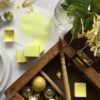 A splash of Art scribe handmade watercolour cadmium lemon paint with pigment, measuring spoon, pans of paint and a wooden box with similar colour items within.