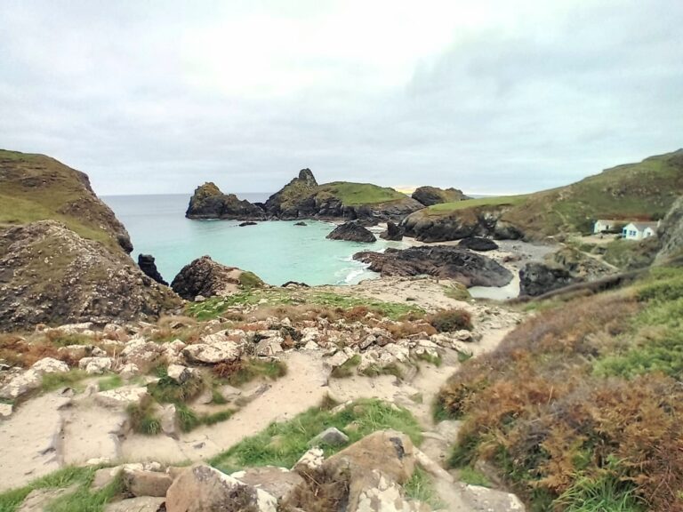 Landscape view overlooking Kynance Cove with turquoise sea and sandy paths.